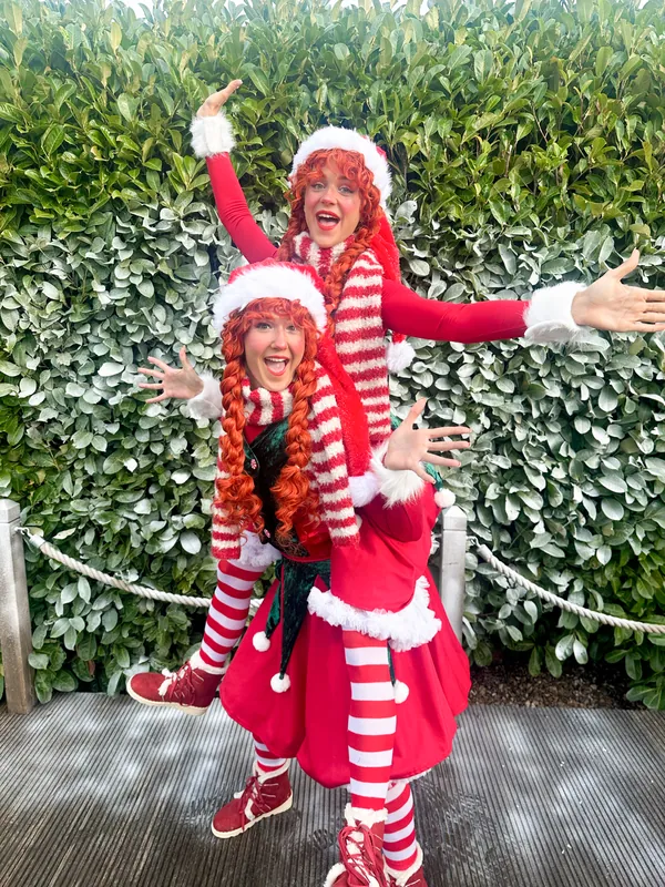 Two festive elf performers in red and white
